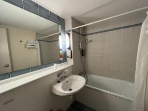 a bathroom with a sink and a mirror and a tub at initial by balladins La Roche-sur-Yon in La Roche-sur-Yon