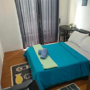a room with a bed with a blue blanket and a table at Mega Tower Transient Home in Baguio