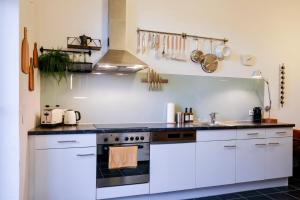 a kitchen with white cabinets and a stove at Kunstvolles Apartment im Zentrum mit Balkon und Parkplatz in Graz