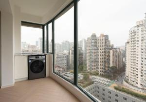 eine Waschmaschine in einem Raum mit großen Fenstern in der Unterkunft EHUB - City View Apt in Xintiandi Area with French Design Spacious 3Bedroom in Shanghai