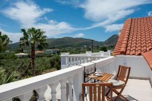 a balcony with a table and chairs and mountains at White Lotus Loft & Apartments in Laganas