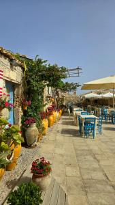 a patio with tables and chairs and potted plants at Pasithea House in Marzamemi