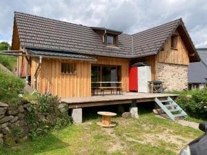 a house with a wooden deck with a red refrigerator at Au croque nature in Soultzeren