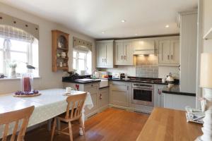 a kitchen with white cabinets and a table with chairs at Legion Cottages in Blakeney