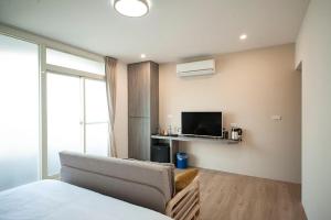 a bedroom with a bed and a couch and a tv at Little Sunshine in Dongshan