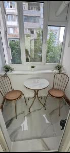 two chairs and a table in a room with two windows at Apartament Daria in Timişoara