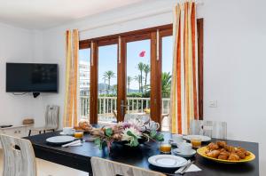 un comedor con una mesa con comida. en YourHouse Reganyol beach apartment, en Puerto de Alcudia