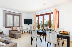 Un comedor y una sala de estar con mesa y sillas. en YourHouse Reganyol beach apartment, en Puerto de Alcudia
