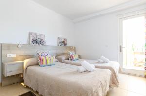 Dos camas en una habitación con paredes blancas. en YourHouse Reganyol beach apartment, en Puerto de Alcudia