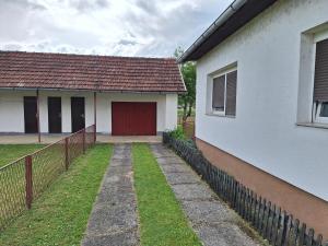 a white house with a red door and a fence at Stefin kutak HOME in Bosanski Novi