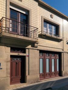 a brick building with brown doors and a balcony at Uporto House Villa in Porto
