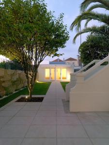 a white house with a tree and a sidewalk at Uporto House Villa in Porto