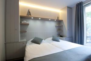 a bedroom with a large white bed and a window at Hotel Bilderdijk in De Haan