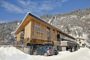 un bâtiment avec une voiture garée dans la neige dans l'établissement Residenz Wildkogelbahnen Top 2, à Neukirchen am Großvenediger