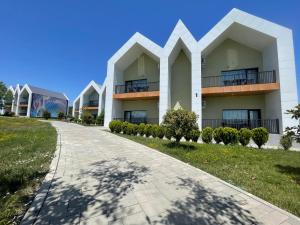 a white building with a walkway in front of it at Arena Apartments & Villas Guba in Quba