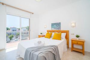 a white bedroom with a large bed with yellow pillows at Jouvacations Villa 2 Freser con piscina compartida in Empuriabrava