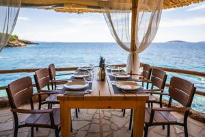 a wooden table with chairs and the ocean in the background at GLamping tents Adriatic - Orebic in Orebić