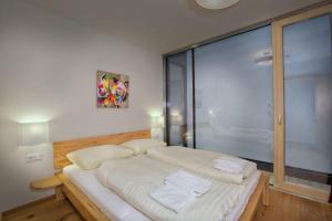 a bed in a room with a large glass window at Residenz Wildkogelbahnen Top 6 in Neukirchen am Großvenediger