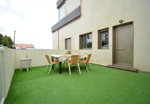 ein Tisch und Stühle auf einer Terrasse mit grünem Gras in der Unterkunft Apartamento con terraza en San Vicente in O Grove