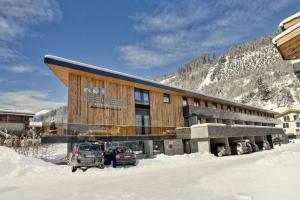 a building with cars parked outside of it in the snow at Residenz Wildkogelbahnen Top 9 in Neukirchen am Großvenediger