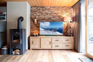 a living room with a tv and a brick wall at Residenz Wildkogelbahnen Top 9 in Neukirchen am Großvenediger