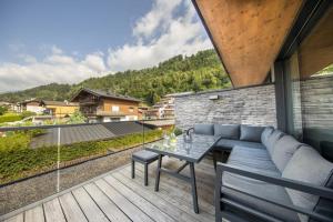 a patio with a couch and a table on a balcony at Residenz Wildkogelbahnen Top 14 in Neukirchen am Großvenediger
