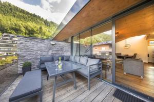 a patio with a couch and a table on a deck at Residenz Wildkogelbahnen Top 14 in Neukirchen am Großvenediger
