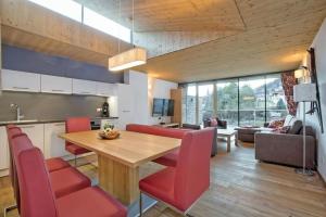 a kitchen and living room with a wooden table and red chairs at Residenz Wildkogelbahnen Top 15 in Neukirchen am Großvenediger