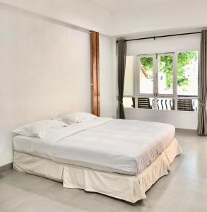 a bedroom with a large white bed with a window at Dad D Resort by Lopburi Inn Resort in Lop Buri
