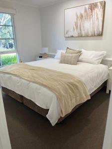 una camera da letto con un letto grande con lenzuola e cuscini bianchi di River Frontage Unit Moama a Moama Altre 29 foto