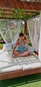 a woman in a dress sitting on a bed at Apartmani Neven in Irig