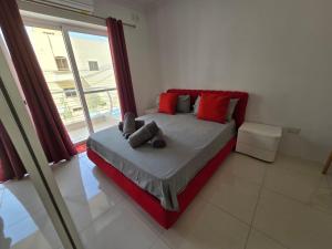 a bed with red pillows in a room with a window at Stunning two bed apartment in St Pauls Bay Malta in St Paul's Bay