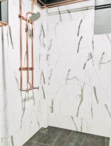 a shower in a bathroom with white marble walls at Dad D Resort by Lopburi Inn Resort in Lop Buri