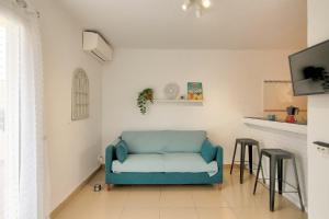 a living room with a blue couch and two stools at Atic Els Pins in L'Estartit
