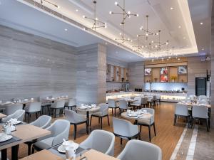 宝安にあるkyriad Hotel, Shenzhen Baoan International Convention and Exhibition Center National Exhibitionのテーブルと椅子とバーのあるレストラン