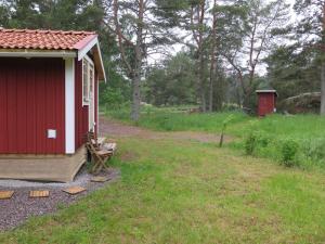 a red shed with a bench next to a field at Dunderfriggan på Möja in Möja