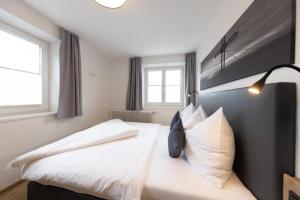 a bedroom with a bed with white sheets and pillows at Haus Schnöll Top 8 in Mittersill +23 photos