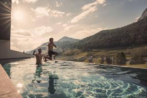 two young boys jumping into a swimming pool at Hotel Continental in Selva di Val Gardena