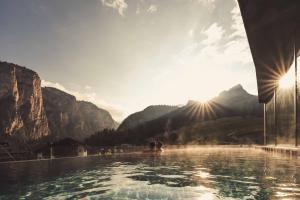 a infinity pool with mountains in the background at Hotel Continental in Selva di Val Gardena