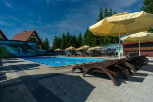 a pool with chairs and umbrellas and a bench with an umbrella at Summit in Yablunytsya