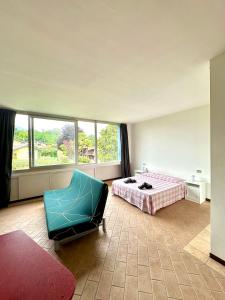 a bedroom with a bed and a chair and a window at Apartment with swimming pool in Reno Di Leggiuno