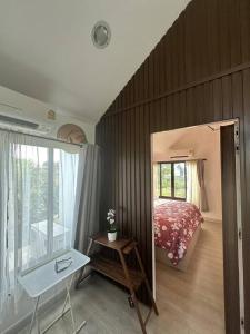 Un dormitorio con una cama, una mesa y un espejo. en Tiny home by the River in Thailand, en Phra Nakhon Si Ayutthaya