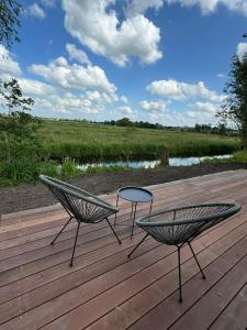 two chairs and a table on a wooden deck at TinyHouse Ochtendgloren in Haastrecht