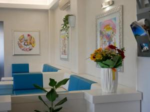 a waiting room with blue chairs and a vase of flowers at Hotel Kon Tiki in Numana