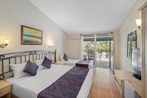 a bedroom with two beds and a tv and a balcony at Alados Otel in Turgut +105 photos