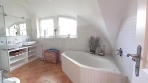 a white bathroom with a tub and a sink at Reethus-am-Hafen Reetdachhaus Hafenblick mit Garten und Blick aufs Wasser in Rankwitz +15 photos