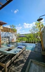 a pool with two lounge chairs and an umbrella at HomeSix Bali in Uluwatu