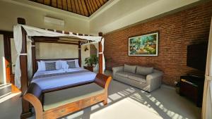 a bedroom with a bed and a couch and a brick wall at HomeSix Bali in Uluwatu