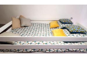 a bed with colorful pillows on top of it at La Maison bleue, un emplacement de choix à Rodez in Rodez