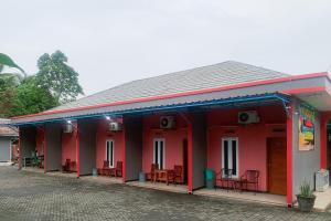 a red building with tables and chairs on it at Hana Losmen RedPartner in Babagan